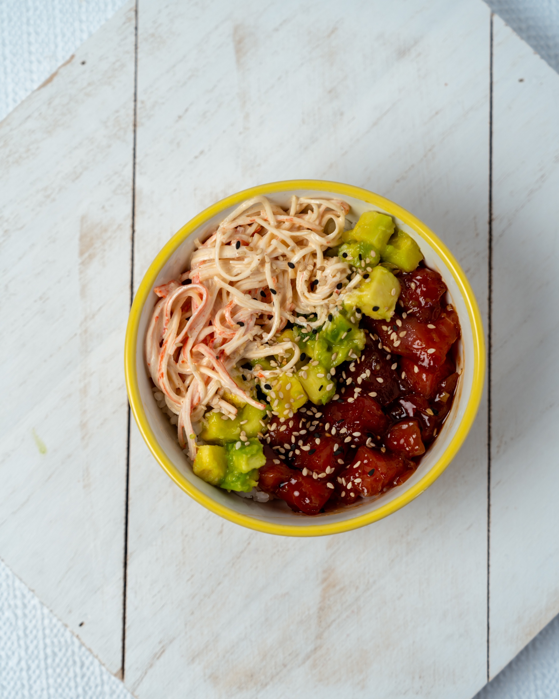 Un poke bowl con atún, aguacate, kani y ajonjolí